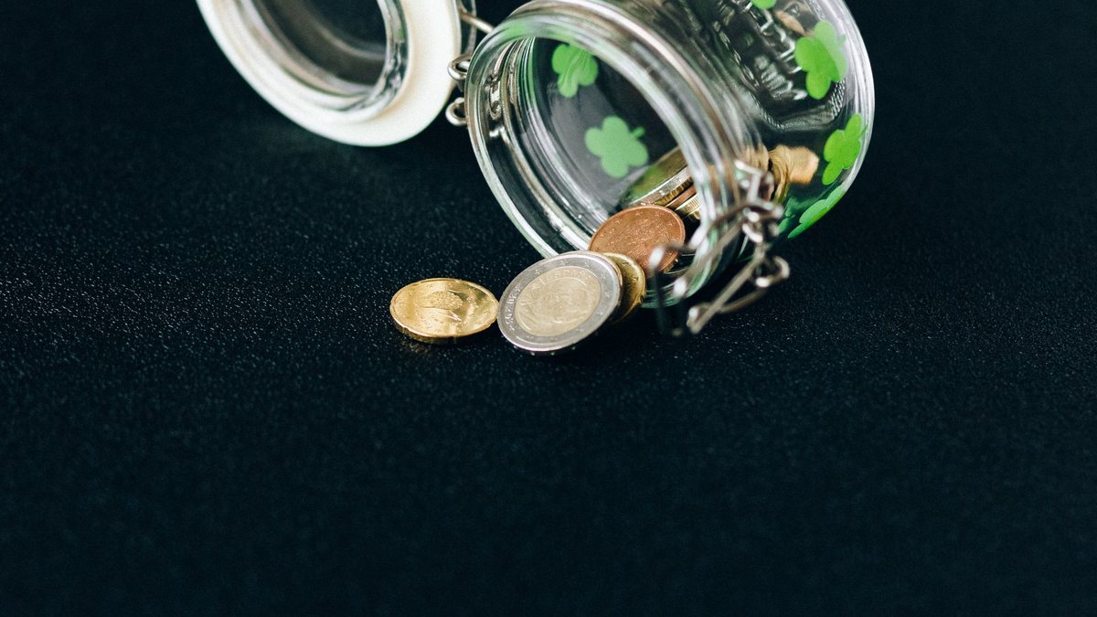Tipped-over glass jar spilling coins onto a dark table