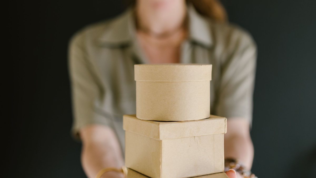 Small business owner holding a stack of kraft gift boxes ready to ship
