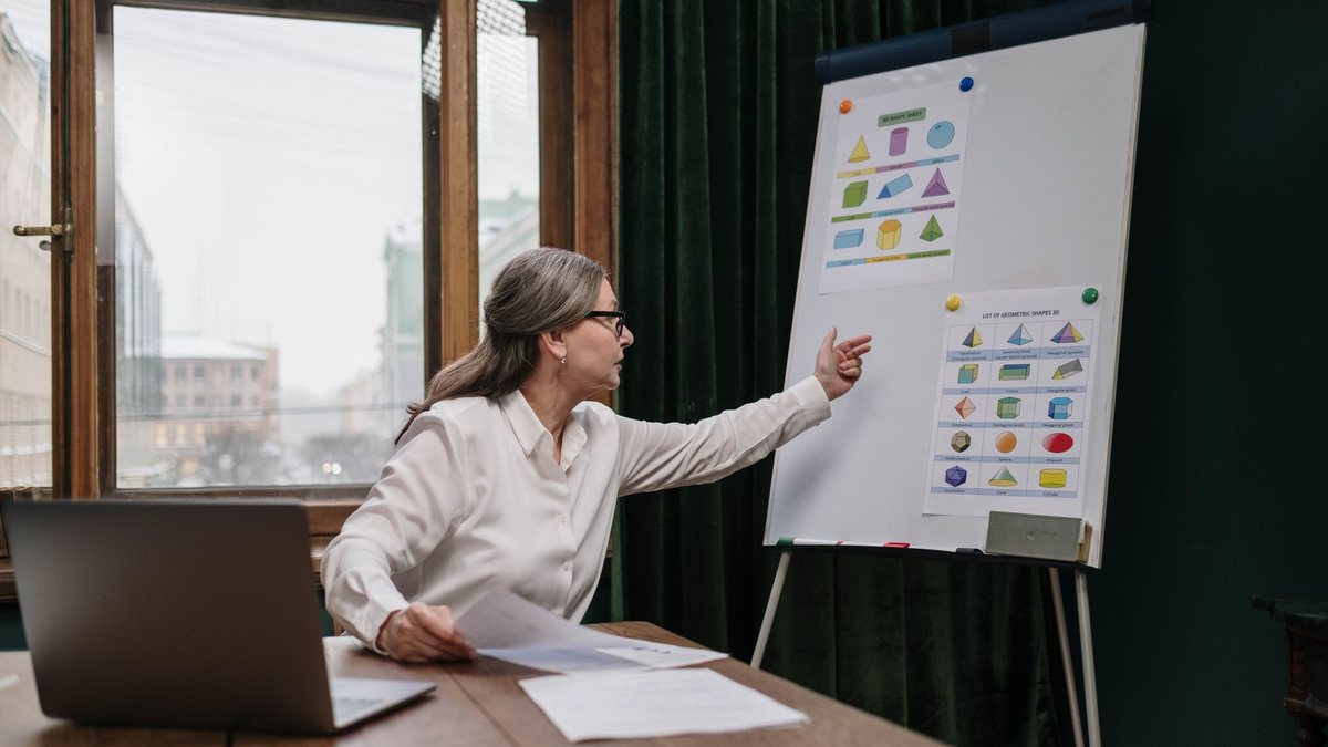 Senior woman presenting at a whiteboard while teaching a class