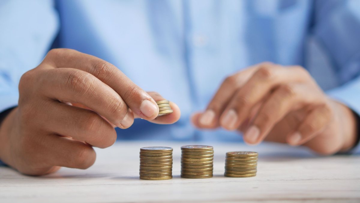 Hands stacking coins into three small towers on a table