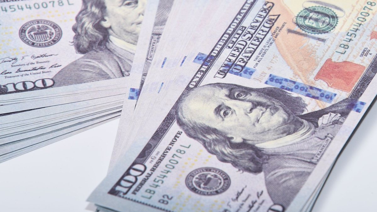 Fanned-out stack of U.S. hundred-dollar bills on a white table