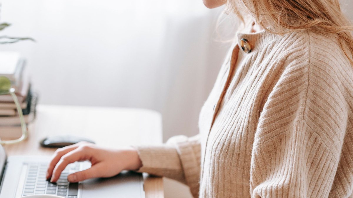 Freelancer typing on a laptop at a bright home desk