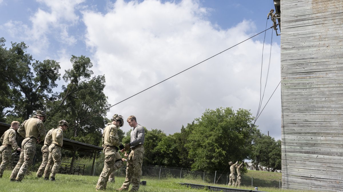 Air Force Tactical Air Control Party airmen gearing up beside a wooden rappel tower at Camp Bullis in Texas