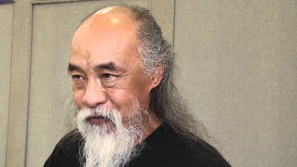 Al Leong with a long white beard and gray hair in a black shirt during an interview