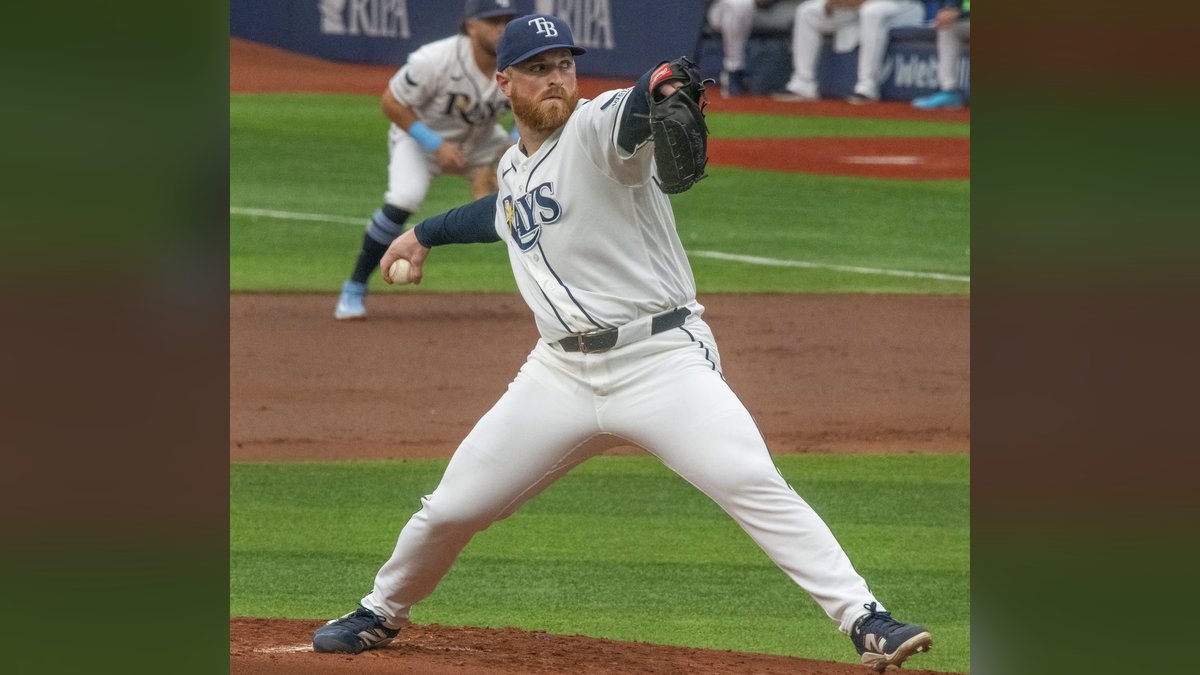 Rays pitcher Drew Rasmussen in a white Rays uniform and navy cap strides toward home plate as he delivers a pitch in June 2026