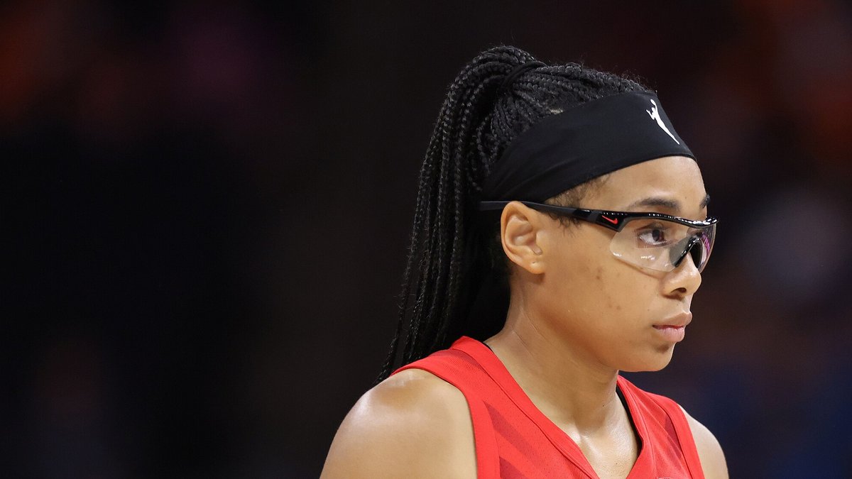 Atlanta Dream guard Allisha Gray in a red jersey with a black headband and clear protective glasses looks off to the side during a 2024 game