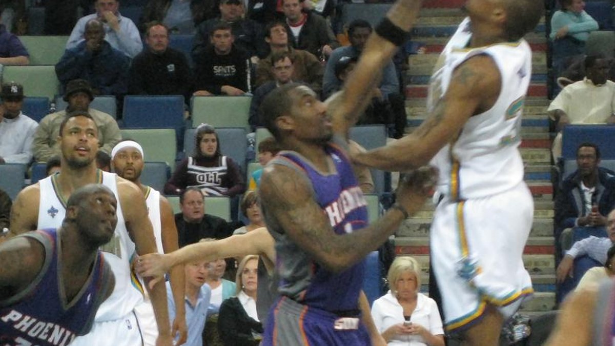 Amar'e Stoudemire in a purple Phoenix Suns jersey fights for position under the basket against the New Orleans Hornets