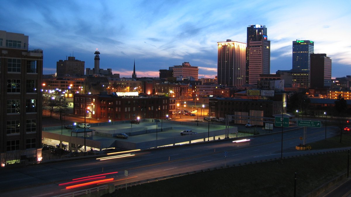 The downtown Little Rock Arkansas skyline glows at dusk above a highway streaked with car lights