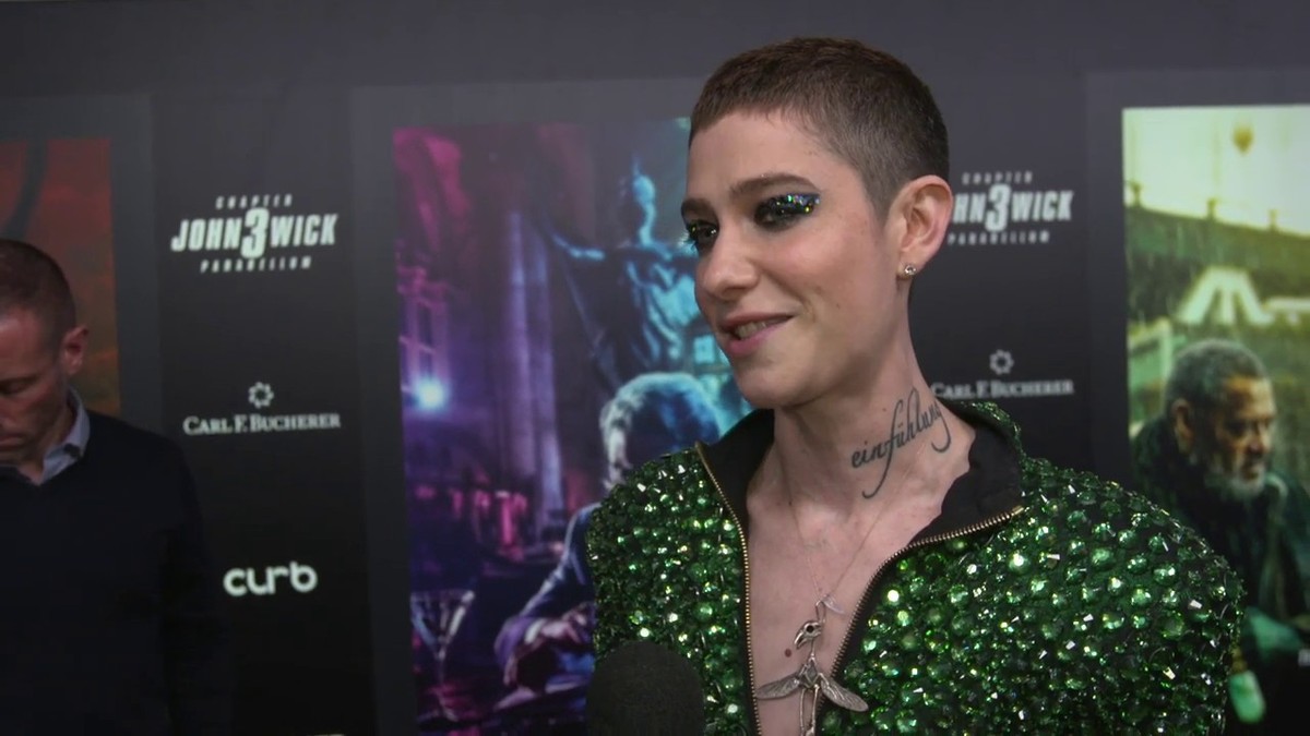 Asia Kate Dillon smiling in a green sequined jacket at the John Wick 3 premiere