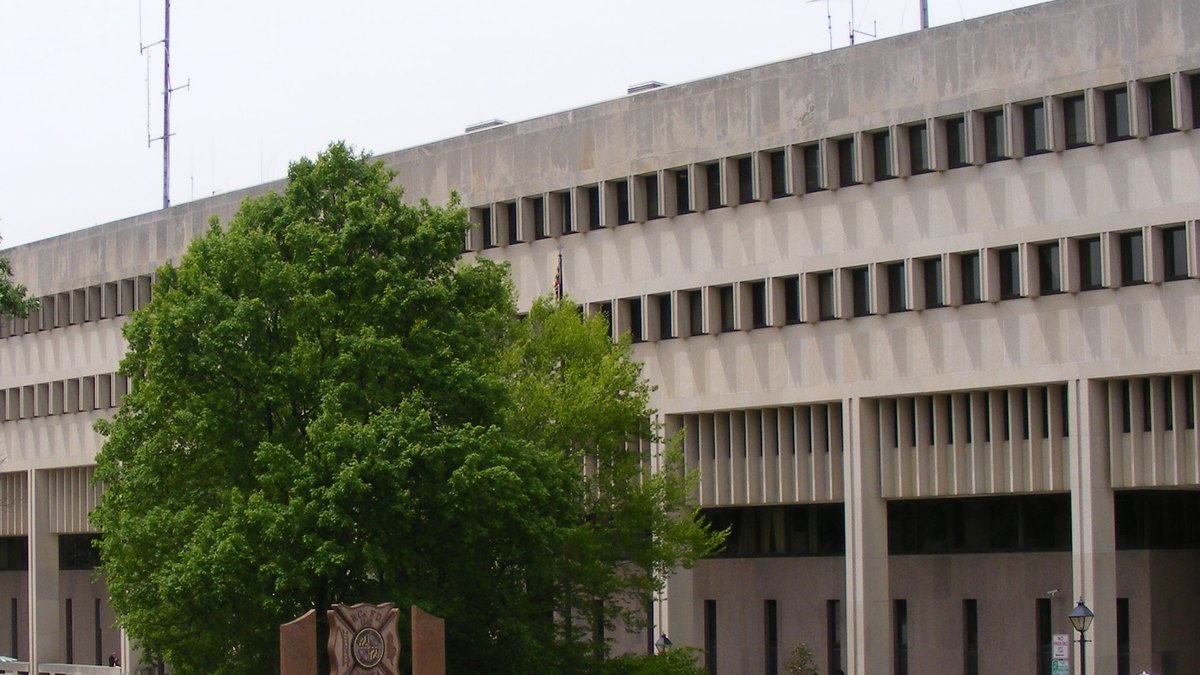 The concrete Baltimore County Courts Building in Towson, Maryland behind a leafy green tree