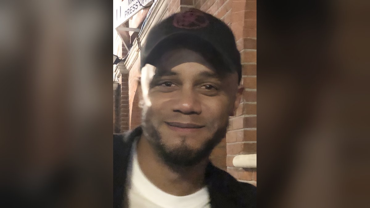 Bayern Munich coach Vincent Kompany smiling in a black cap and dark jacket outside a stadium after a match in December 2023