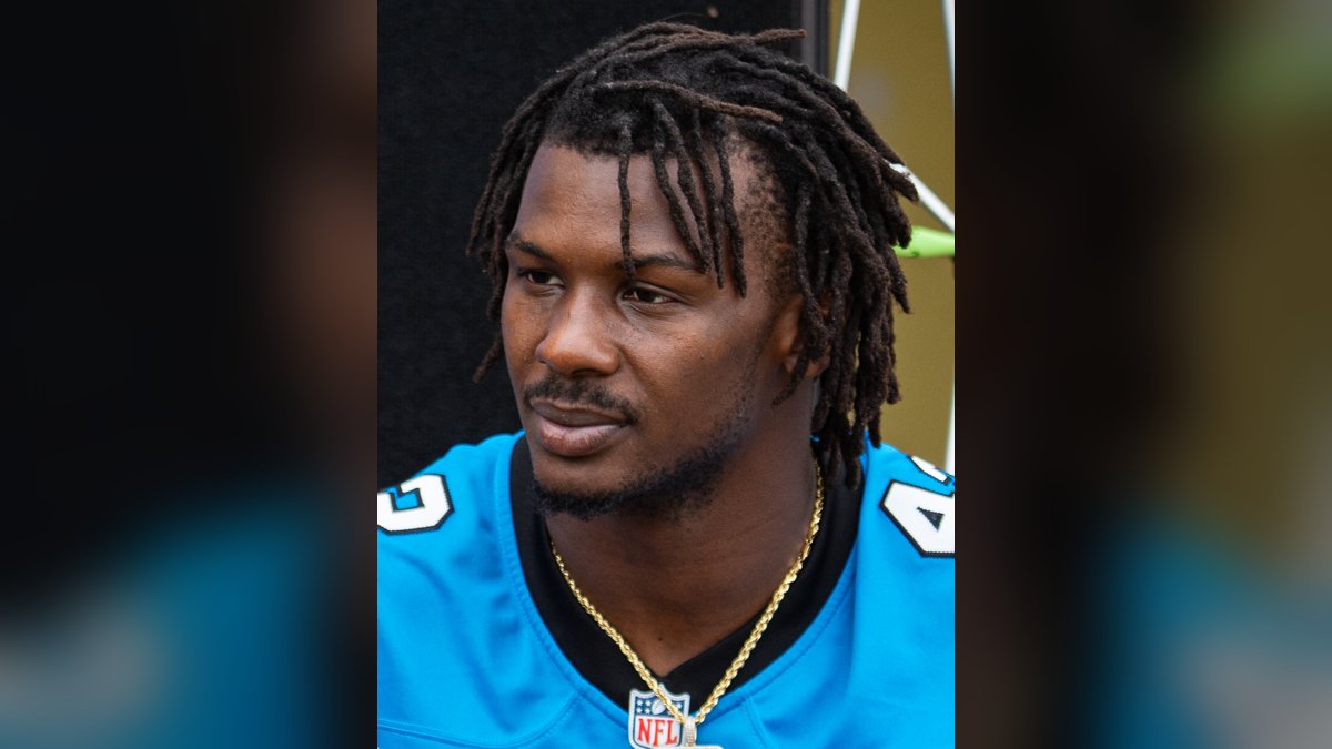 Sam Franklin Jr. in a blue Carolina Panthers jersey and gold chain at a June 2024 community meet and greet
