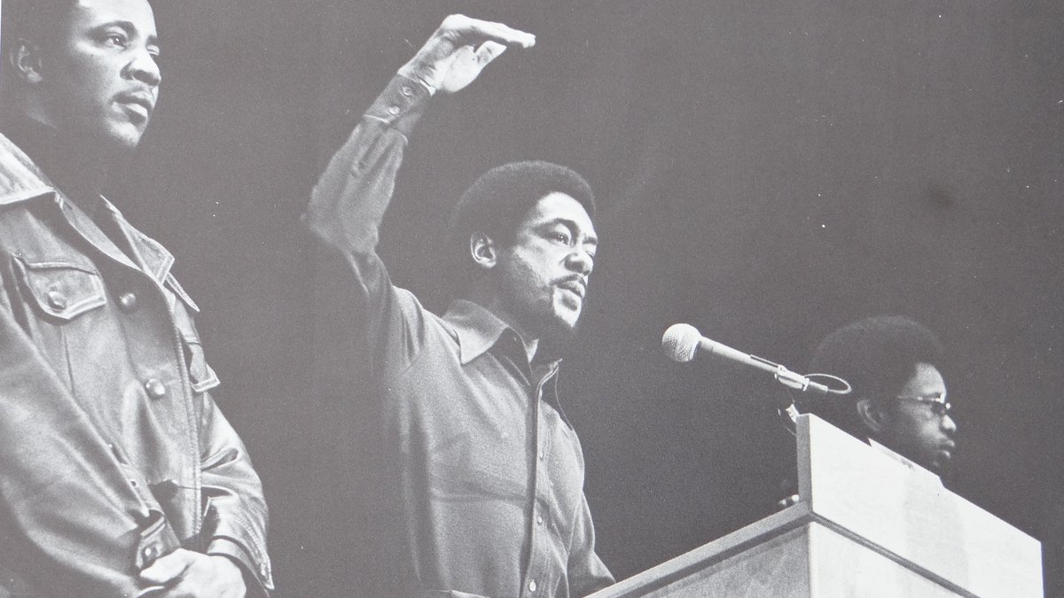 Black-and-white photo of a speaker raising a fist at a 1971 rally where Black Panther co-founder Bobby Seale spoke