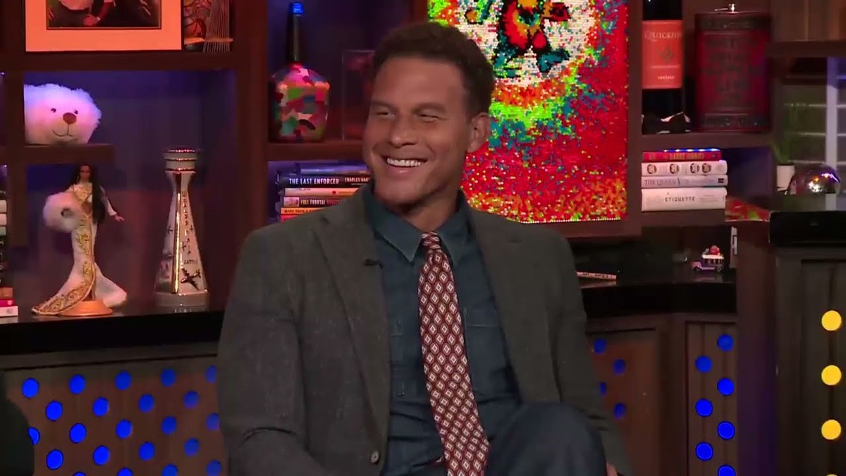 Blake Griffin grinning in a gray blazer and patterned tie on a talk show set