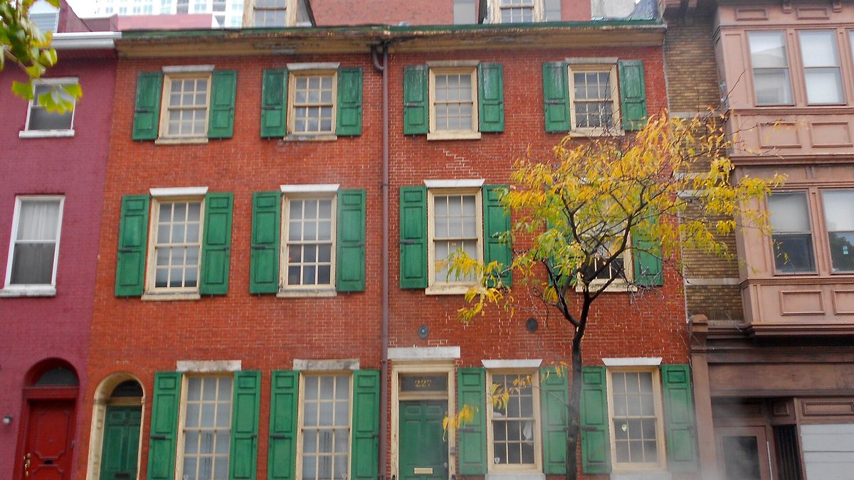 Red brick Philadelphia row houses with green shutters along a city street
