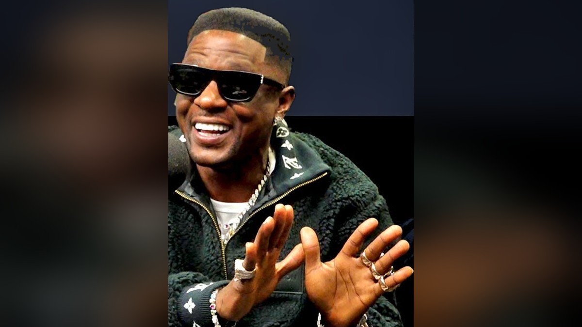 Boosie Badazz in dark sunglasses and a green fleece jacket during a radio interview