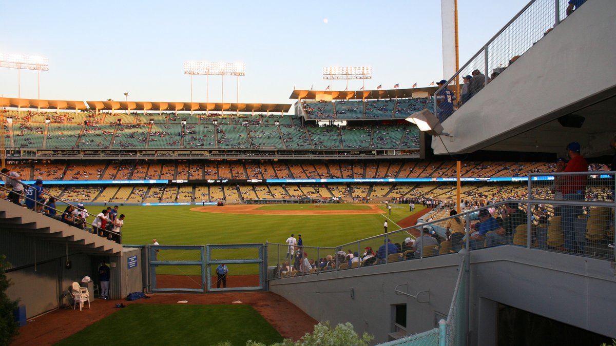 Dodger Stadium's green field and tiers of seats seen from beside the home bullpen on a sunny afternoon