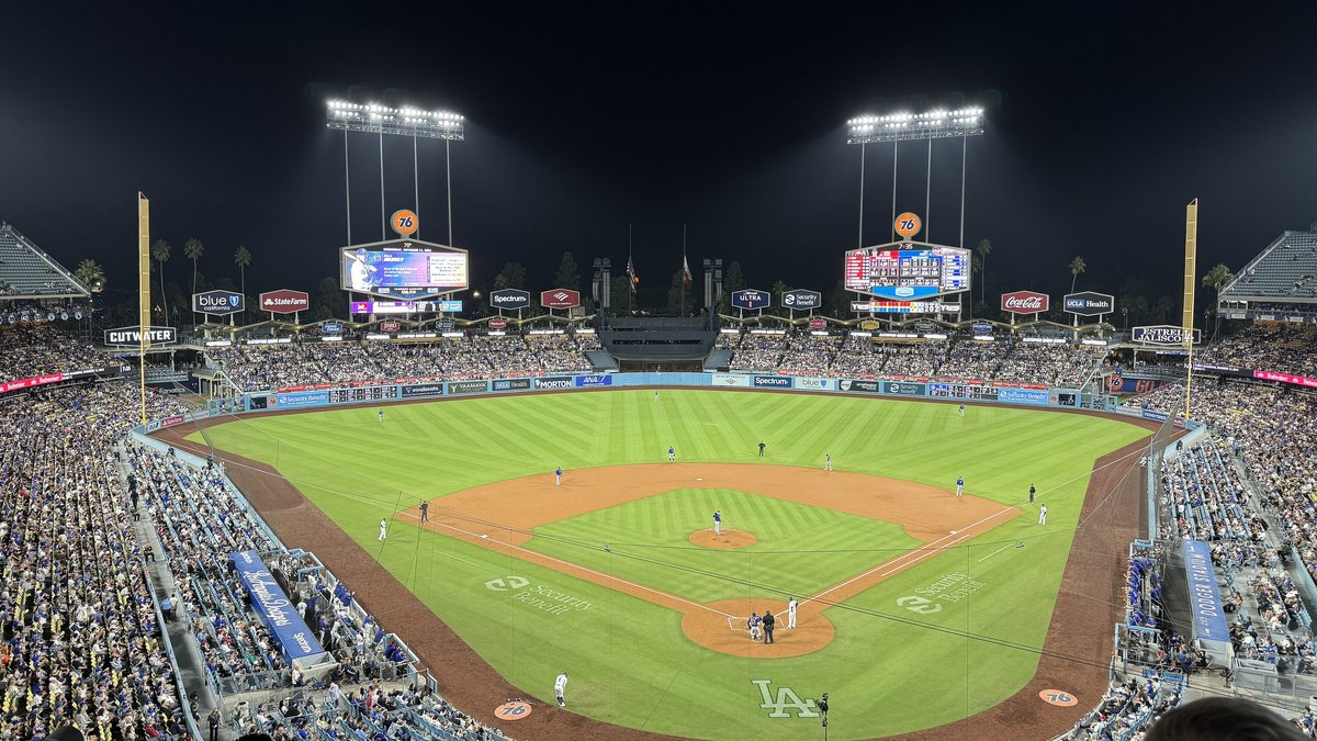 Dodger Stadium under the lights at night with a full crowd watching a game from the upper deck