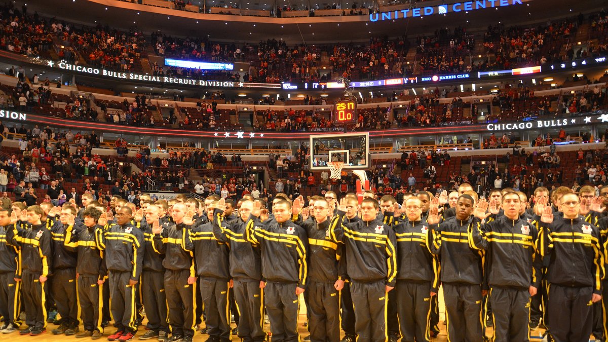Packed stands at the United Center in Chicago during a Bulls game, with a group of military recruits standing on the court