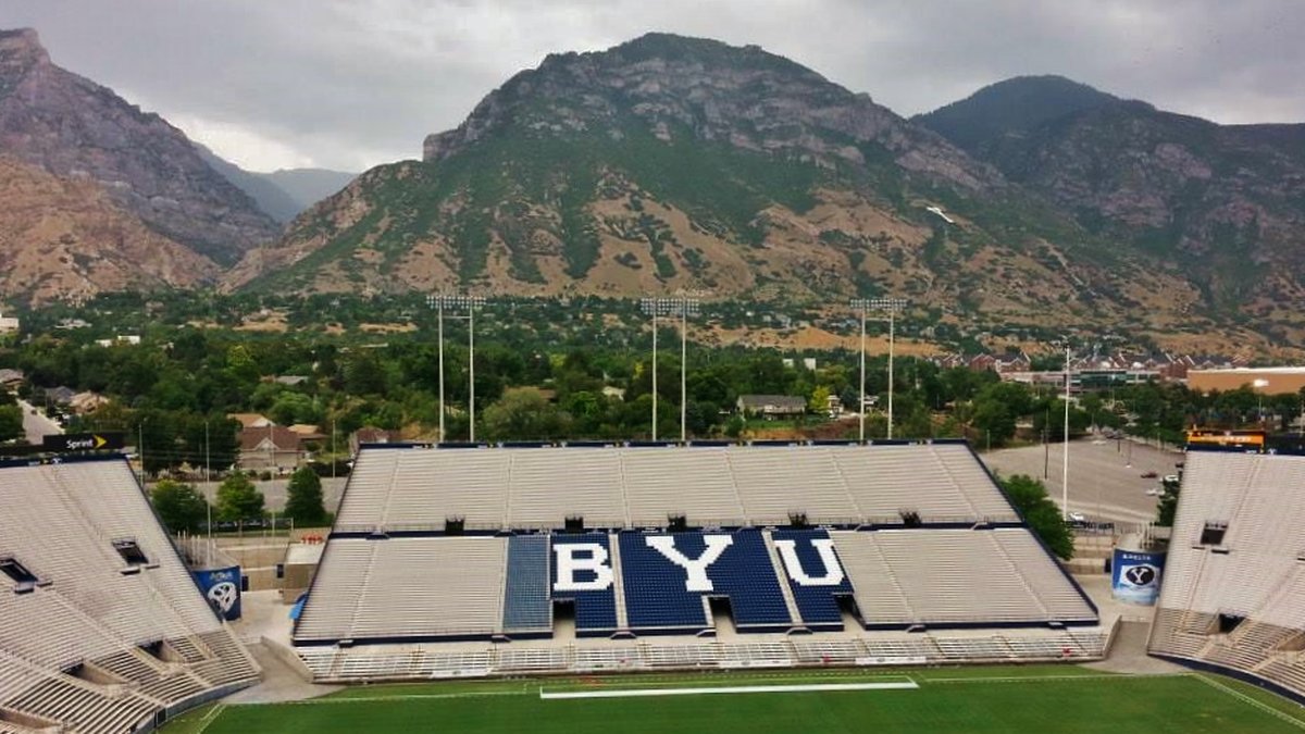 Empty LaVell Edwards Stadium at BYU with the blue BYU letters in the stands and Y Mountain rising behind it in spring