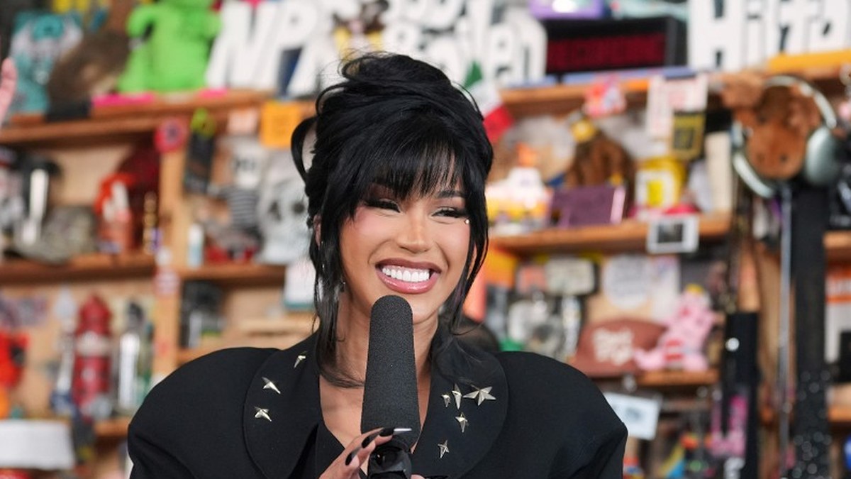 Cardi B smiling at a microphone in a black studded blazer at the NPR Tiny Desk