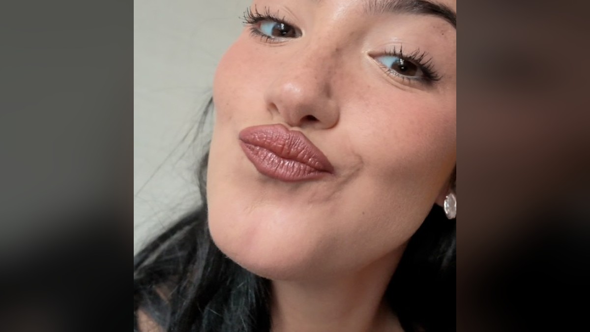 Charli D'Amelio with dark hair pulled back making a playful kissy face