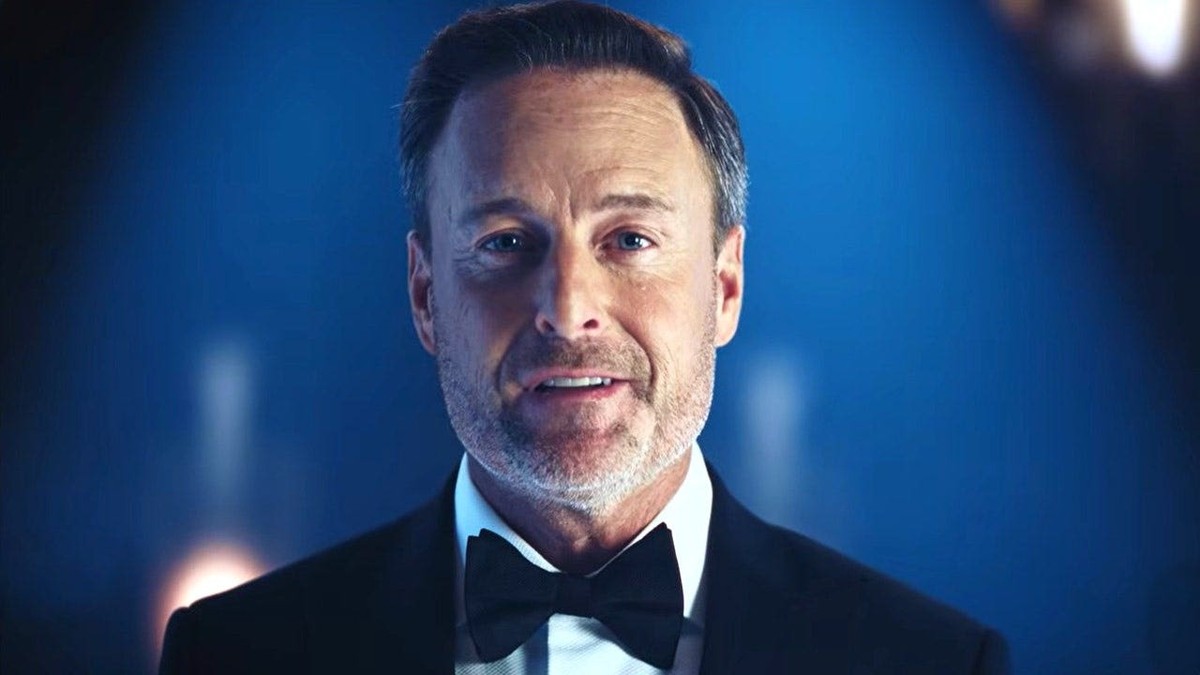 Chris Harrison in a black tuxedo and bow tie against a deep blue backdrop