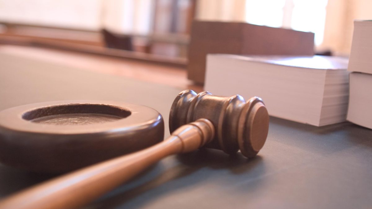 A judge's gavel resting on a courtroom bench