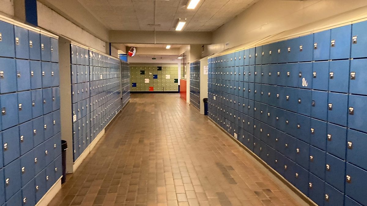 An empty public school hallway lined with blue lockers
