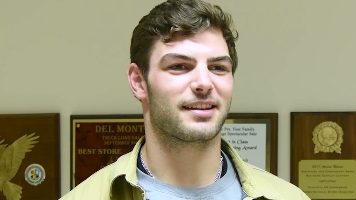 Bears tight end Cole Kmet smiling in a tan jacket during a 2023 visit to a military community