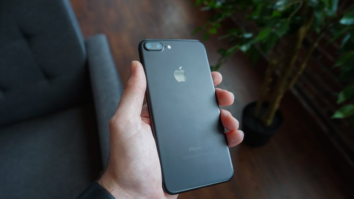 A hand holding a black smartphone inside a home
