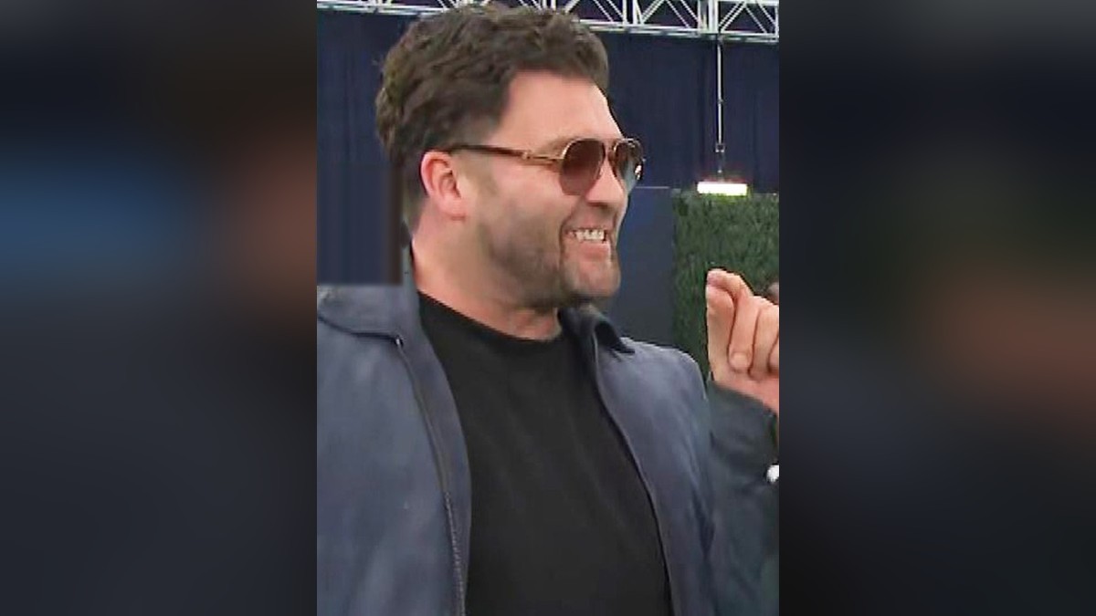 CT Tamburello grinning in aviator sunglasses and a gray jacket on a red carpet