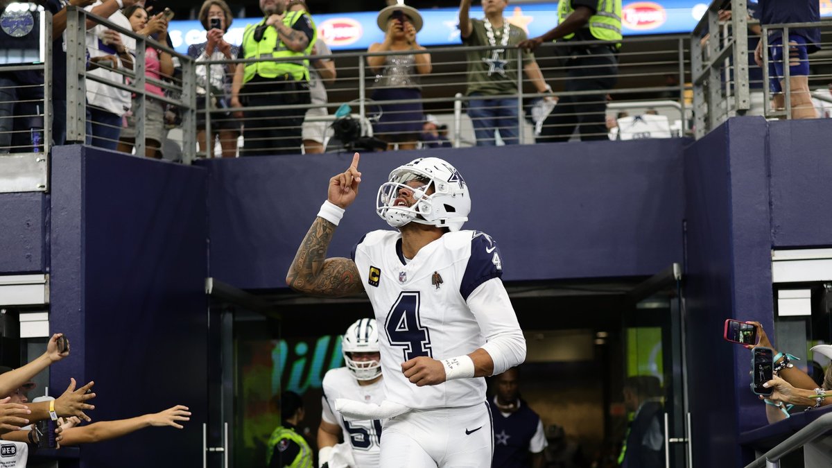 Dak Prescott pointing to the sky as he runs out of the tunnel at AT&T Stadium