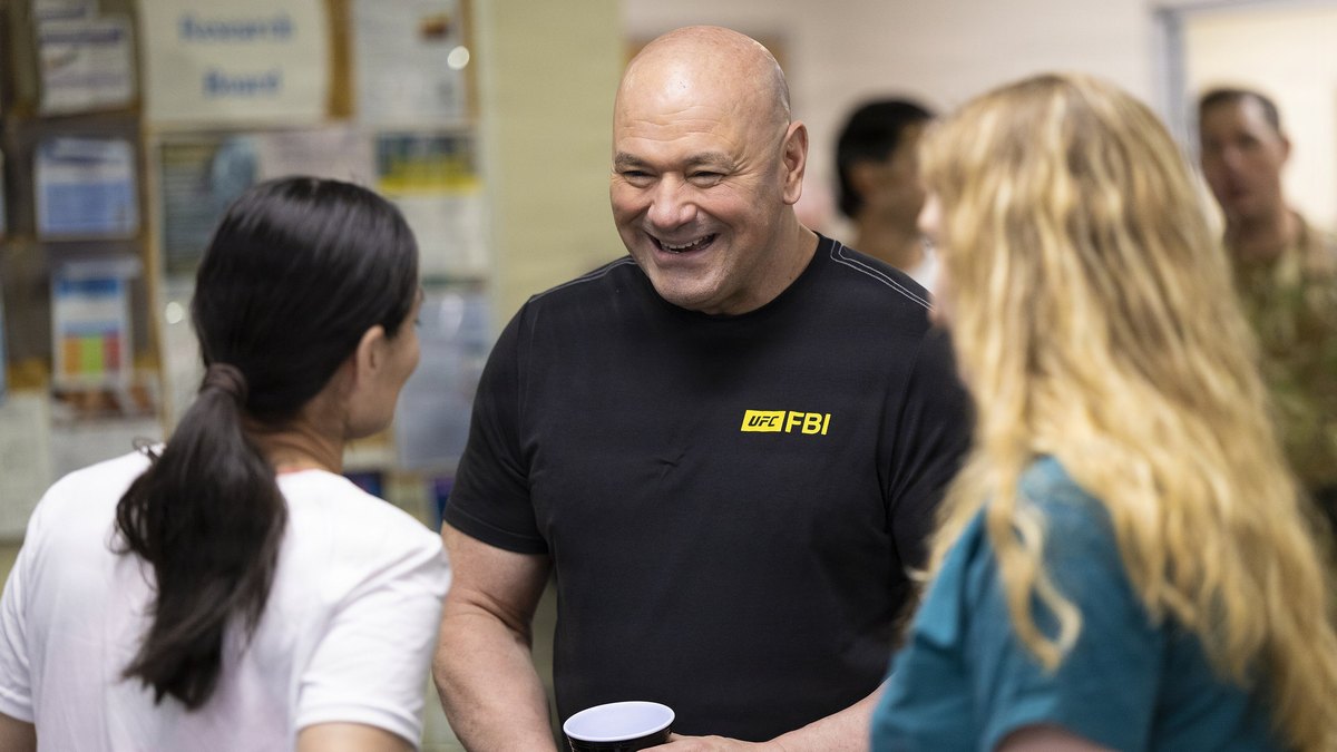 UFC CEO Dana White smiles in a black UFC T-shirt while talking with staff and patients at Walter Reed medical center