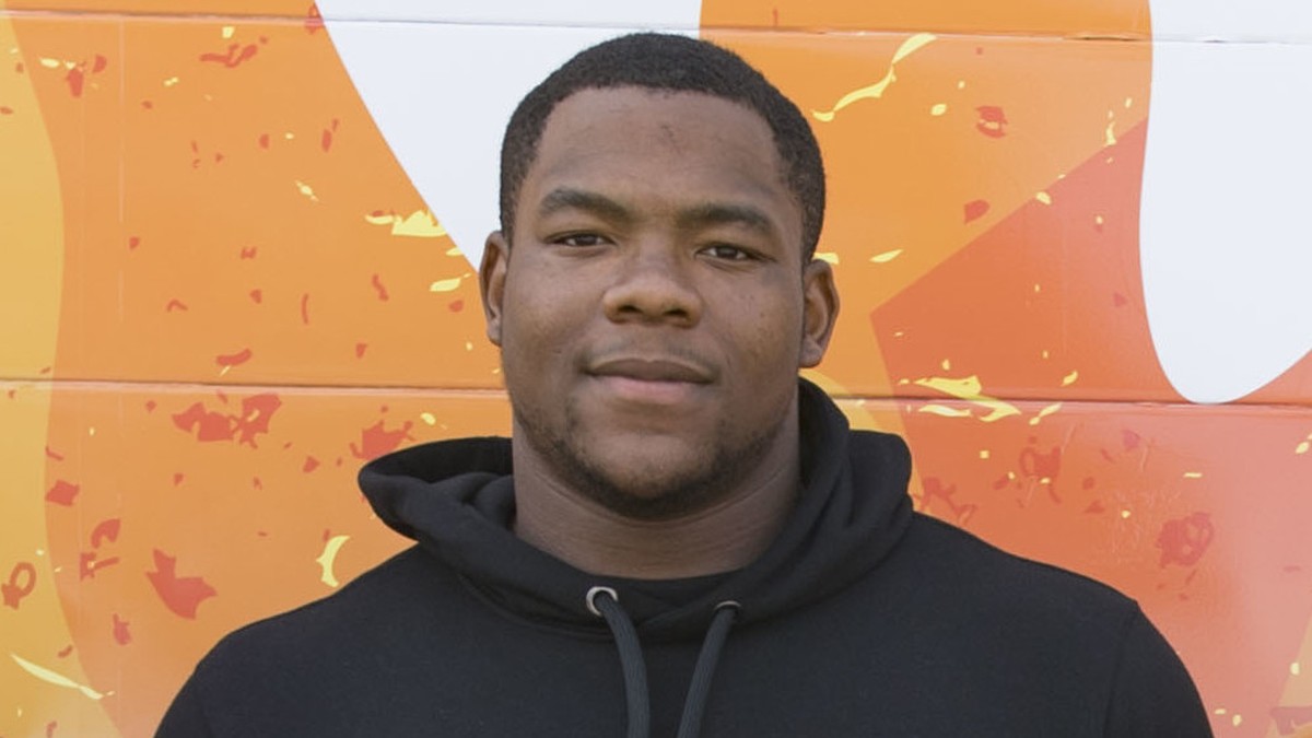 Daron Payne smiling in a black hoodie in front of a bright orange mural