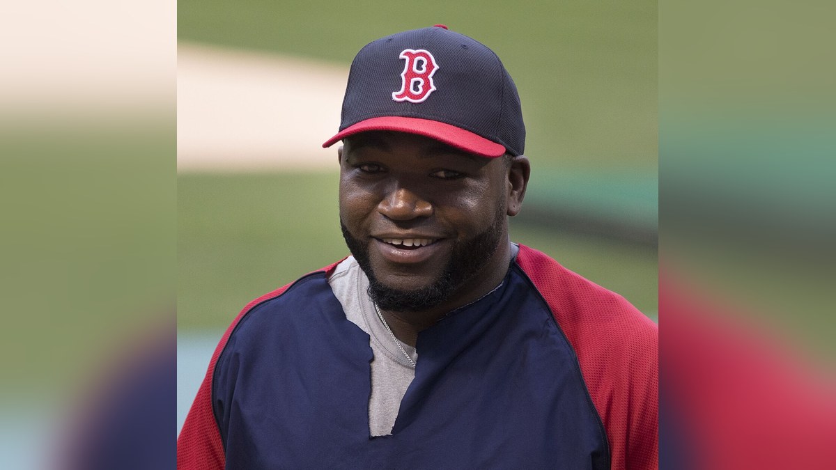 David Ortiz smiles in a Boston Red Sox cap and jacket in 2013