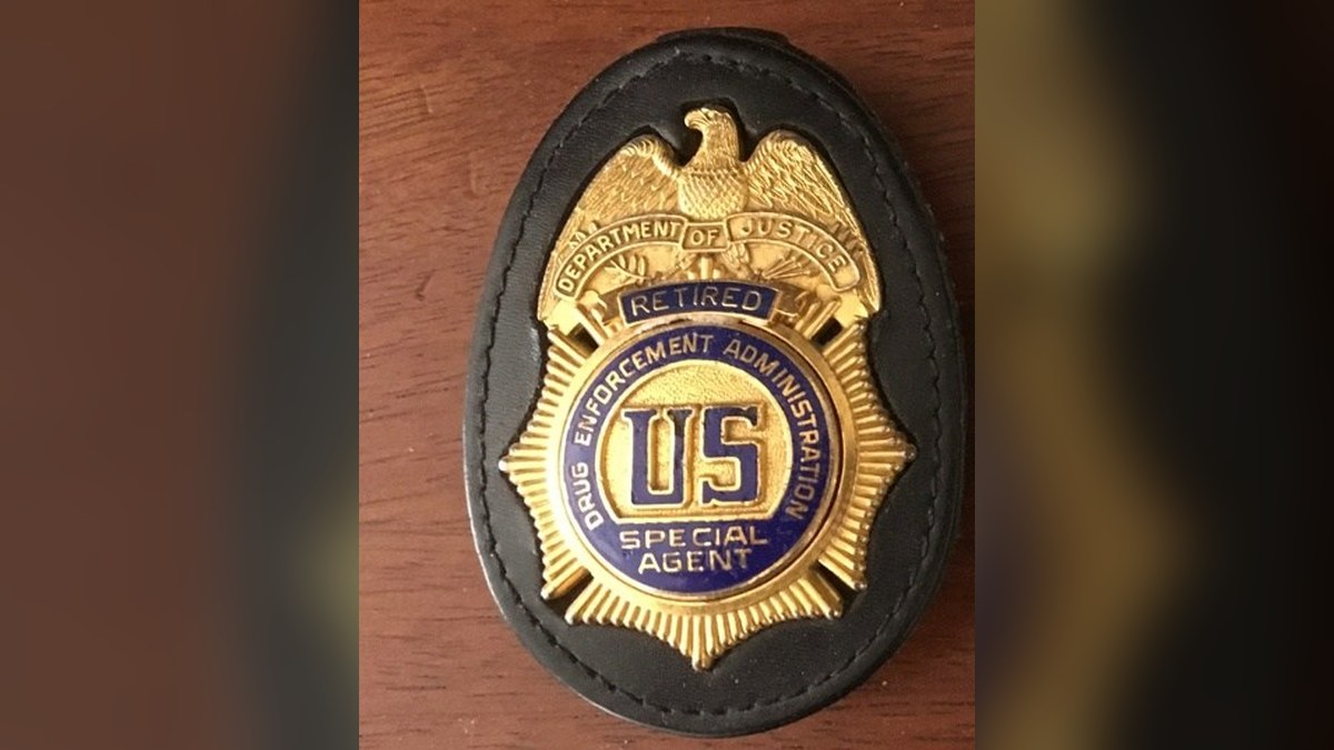 A gold Drug Enforcement Administration special agent badge in a black leather holder