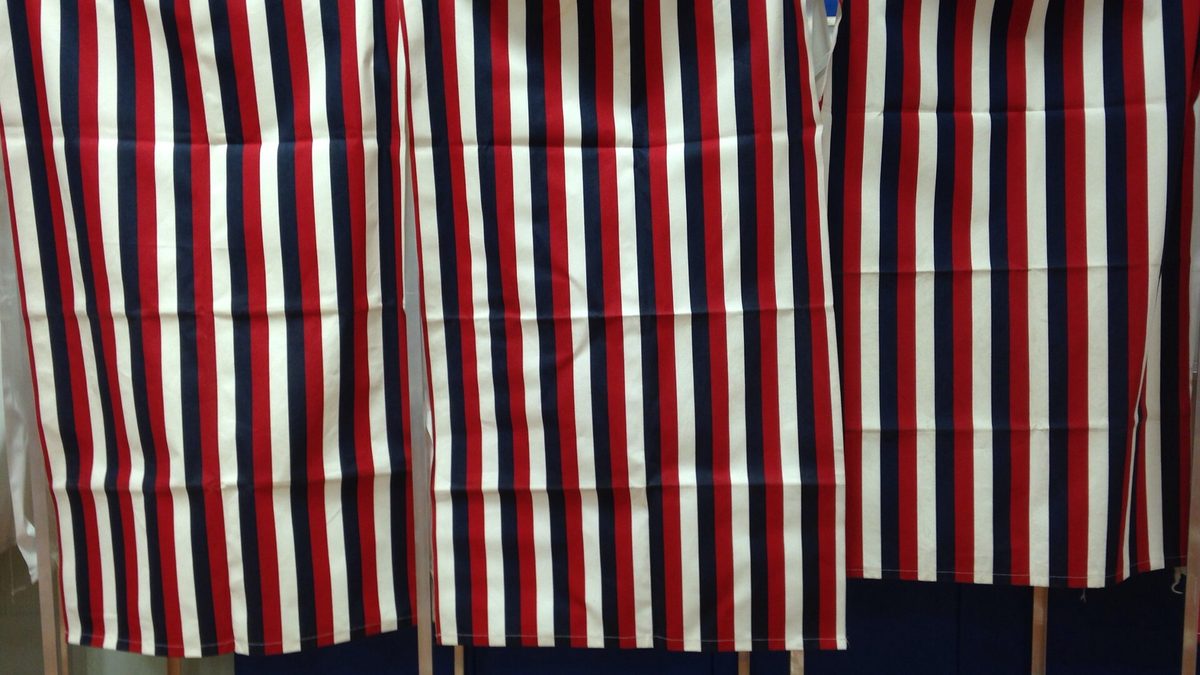 Red, white and blue curtained voting booths at a polling place