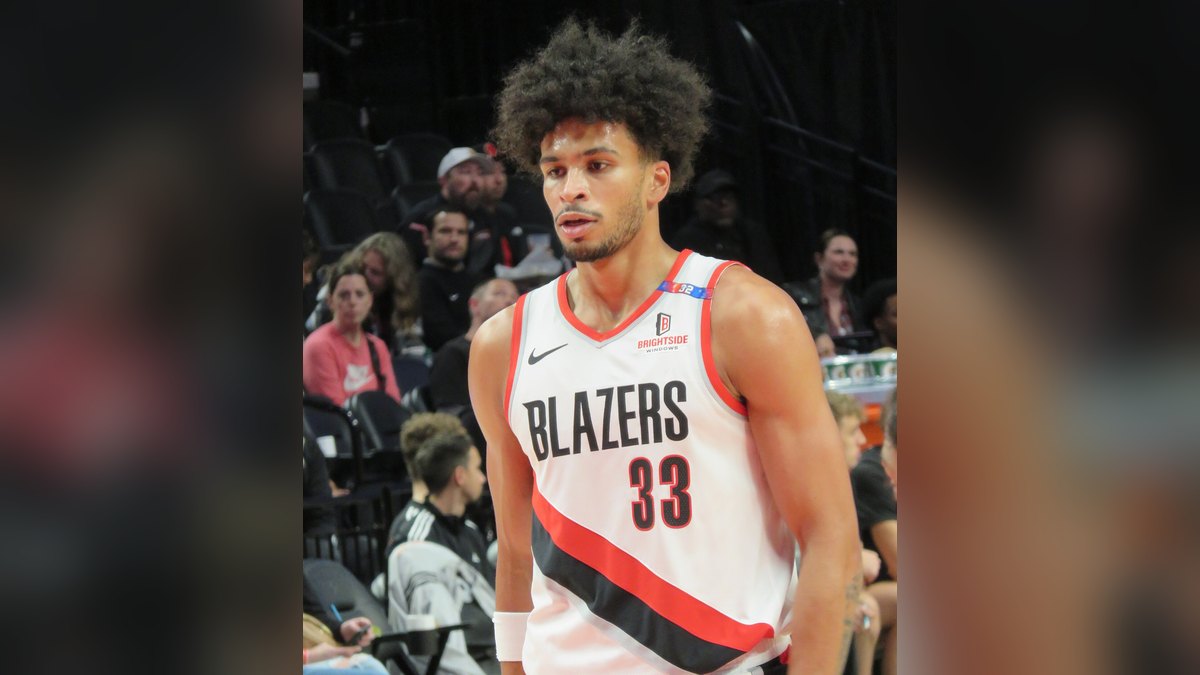 Trail Blazers forward Toumani Camara in his white No. 33 home jersey stands on the court as fans watch from the stands