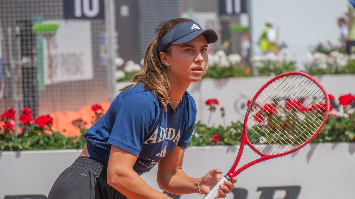 Iva Jovic in a navy visor and shirt waits to return serve on a clay court in Rome
