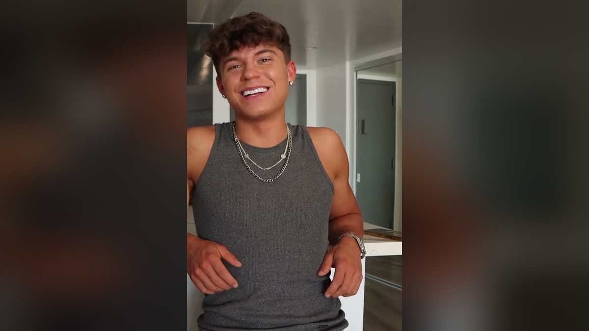 Adult film actor Drake Von smiling in a gray tank top during a sit-down interview