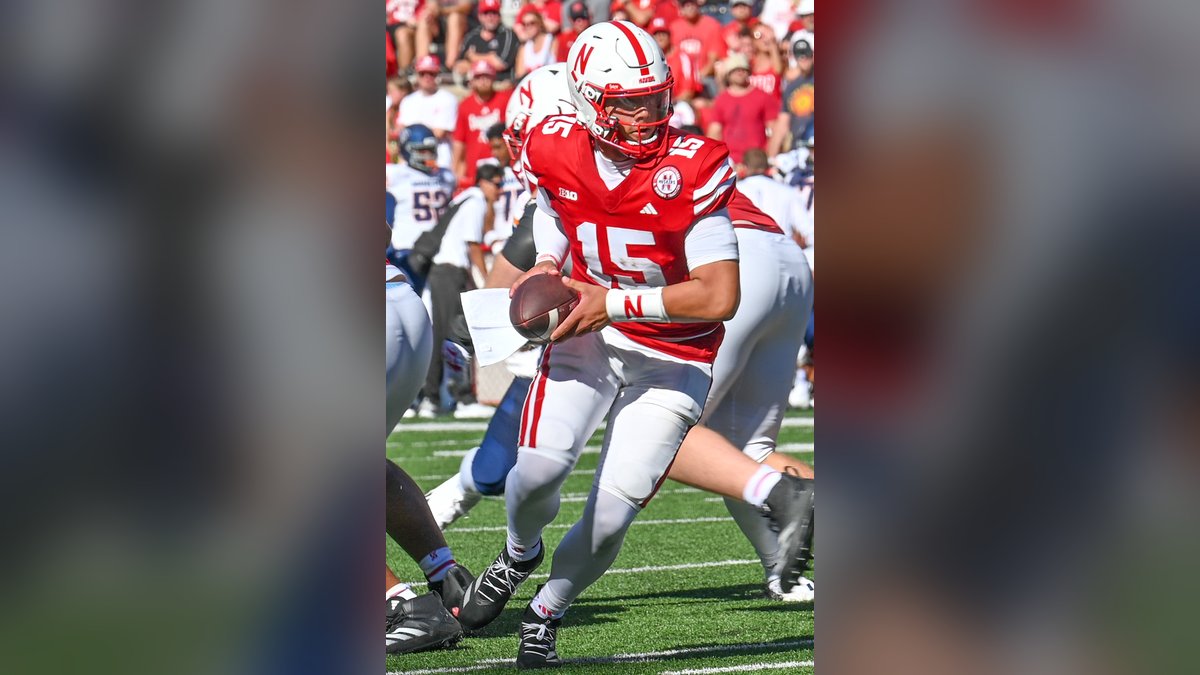 Dylan Raiola in a red Nebraska No. 15 jersey and white helmet turns to hand off the ball during a 2024 game in Lincoln