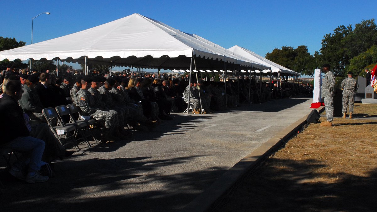 Soldiers and families seated under white tents at a Fort Hood memorial ceremony