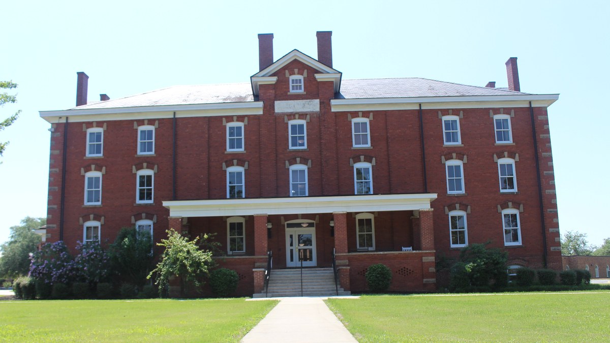 Red brick Huntington Hall with a white columned entrance behind a green lawn on the Fort Valley State University campus