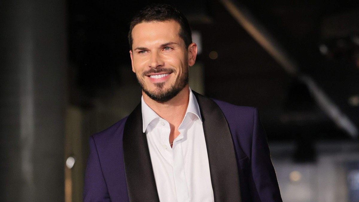 Gleb Savchenko smiling in a purple tuxedo jacket and open white shirt