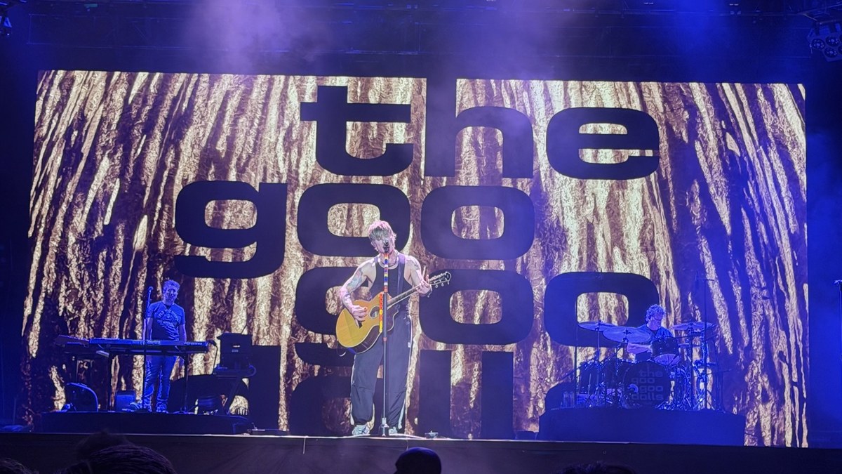 The Goo Goo Dolls performing on stage in front of a giant glowing band logo screen