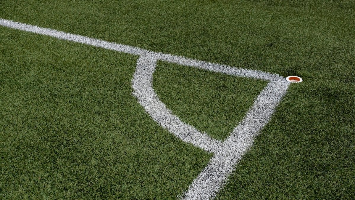 A white corner marking on a green artificial turf field