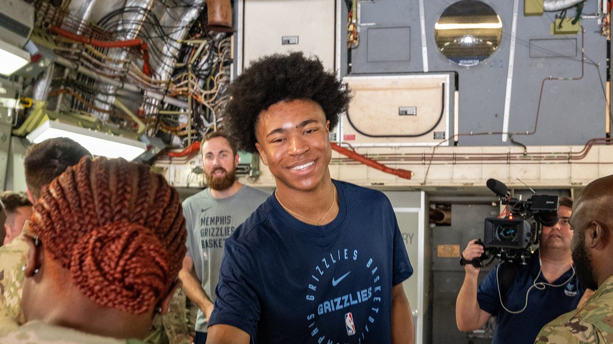 Grizzlies forward Jaylen Wells smiles in a navy Grizzlies T-shirt while greeting airmen inside a cargo plane in Memphis