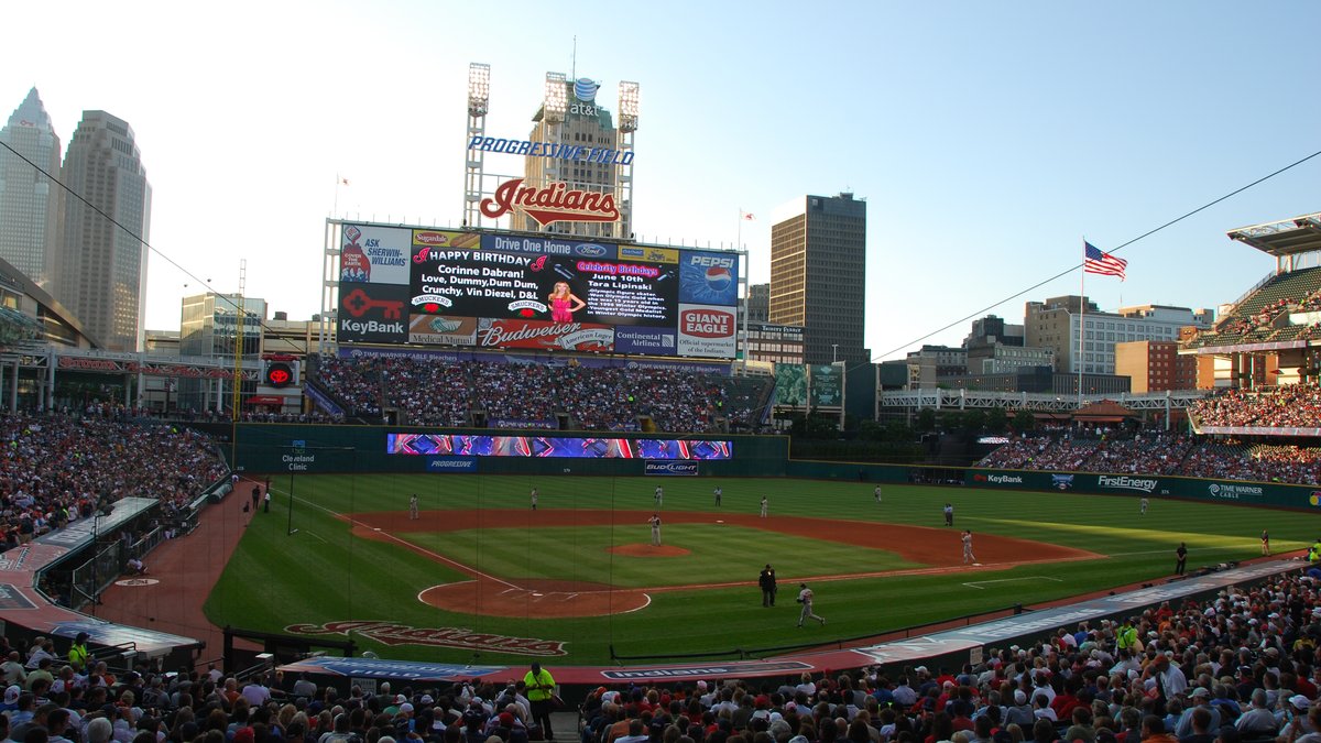 Fans fill Progressive Field in Cleveland as the sun sets over the downtown skyline behind the scoreboard