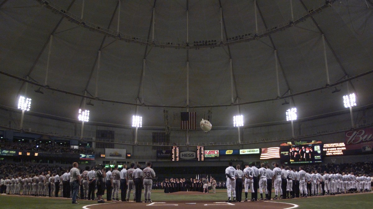 Two teams line up along the baselines under the domed roof and bright lights of Tropicana Field in St. Petersburg